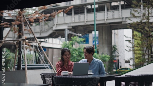 Photography Businesspeople collaborating over laptop, sipping coffee at bustling bangkok out