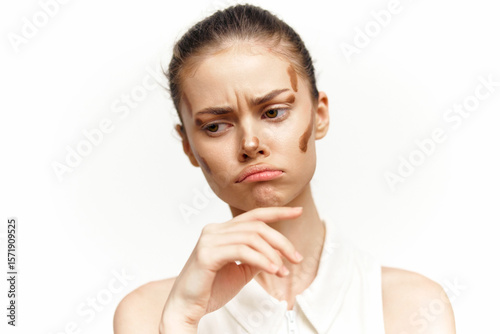 Pensive young woman with a complicated expression showcasing natural beauty and makeup concept against a plain background.