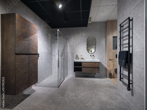 Modern luxury bathroom with glass shower enclosure, floating vanity, and black towel radiator on grey stone walls