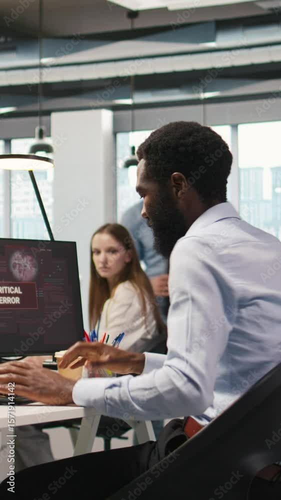 Vertical video Programmer in office requesting help from coworkers to fix critical error warning. IT employee and colleagues brainstorming how to fix computer bug affecting systems, camera A