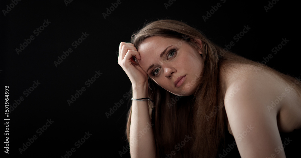 Obraz premium Sad young woman resting her head on her hand, showing loneliness and sadness