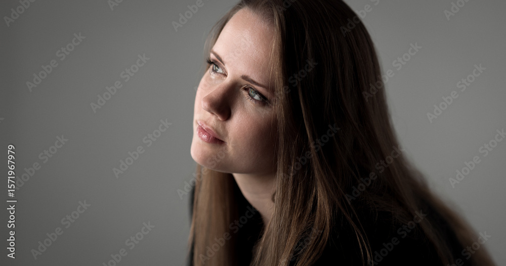 Studio portrait of a young Caucasian woman looking up with a pensive and hopeful expression Studio portrait of a young Caucasian woman looking up with a pensive and hopeful expression