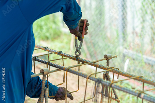 A worker is using pliers to tie rebar wire.