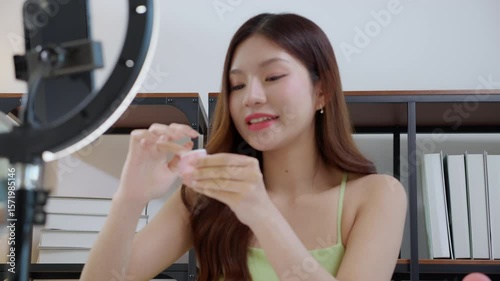 Beauty young asian woman applying cream on facial for wrinkles while looking mirror at home, beautiful woman applying lotion moisturizer on cheek, skincare and beauty, self-care routine in cozy.