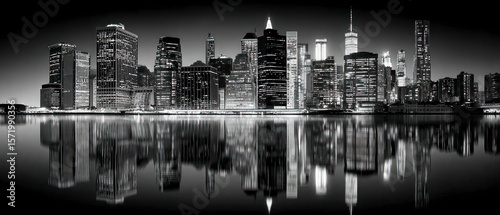 Illuminated modern city skyline reflected in calm water at night black and white panorama
