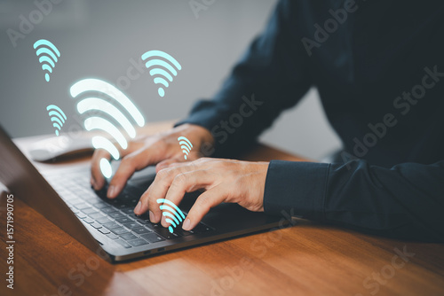 Businessman using laptop with floating Wi-Fi icons, symbolizing wireless internet connection, online communication, remote access, remote work, and network connectivity in a digital workspace.