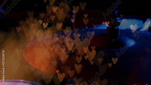 Off-screen drumstick striking cymbal causing vibrating glow stirring smoke hearts visualizing music