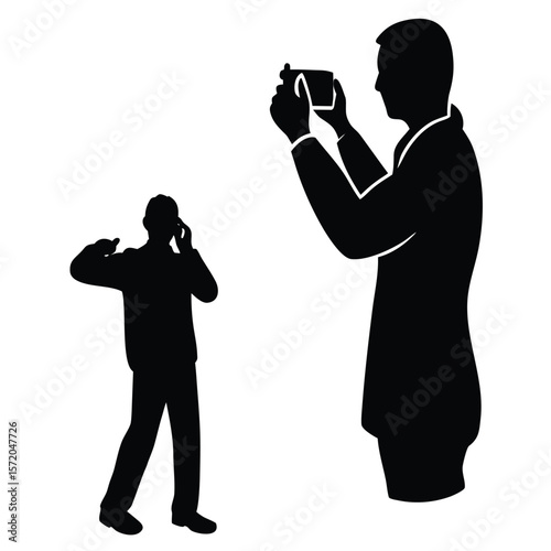 Two ethnic men interact one photographs while the other talks using his cell phone in silhouette