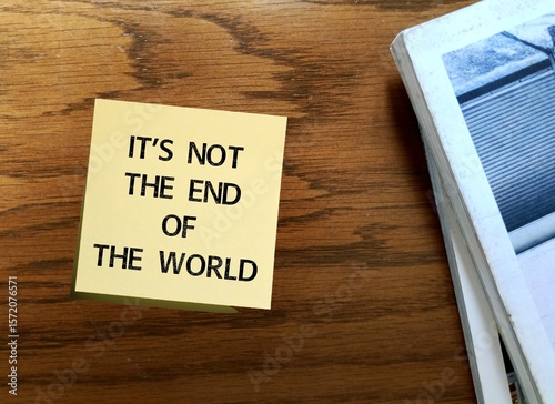 Vintage table with note written - It's not the end of the world - means not the worst thing that could happen - consequences of situation not bad as might seem at first