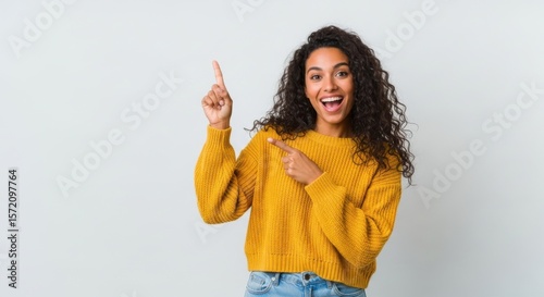 Excited young woman points up and forward with a joyful expression
