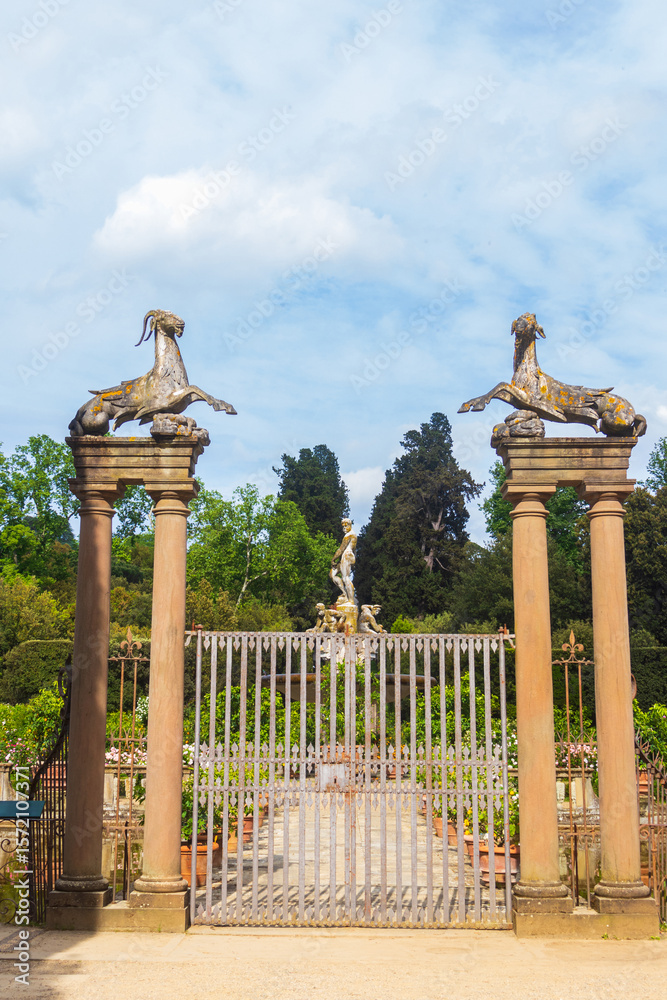 Fototapeta premium Entrance of the Isolotto in Boboli Gardens, Florence, Italy. An iron gate, large columns with Capricorn statues on top