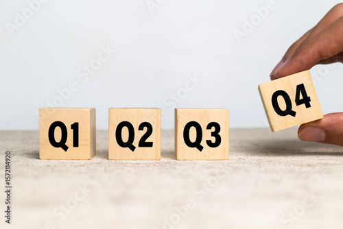 male hand put wooden cubes with q1, q2, q3, q4 symbol isolated on white background. concept of quarterly report annual