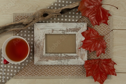 Photo frame, lemon tea and red leaves on wooden table