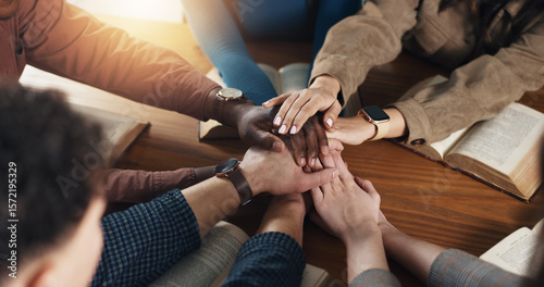 Stack of hands, bible and people by table for unity, solidarity and support at religion study. Trust, top view and prayer group with partnership and collaboration with holy book for worship community