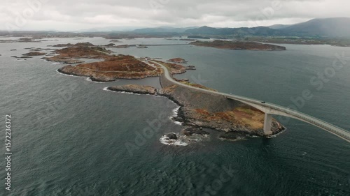 Atlantic ocean road displays rugged terrain meeting small islands. Road gracefully curves over water demonstrating remarkable engineering in Norway