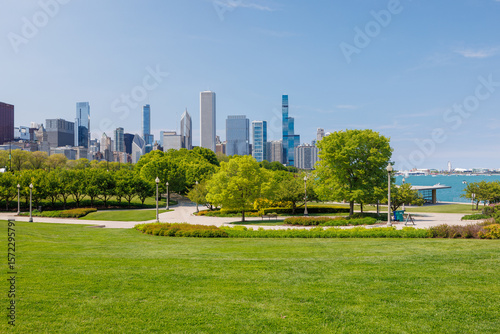 Sunny view of downtown Chicago with iconic skyscrapers rising above a lush green park meadow