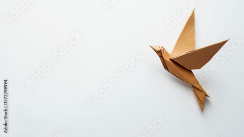 Tan origami bird in flight on white background.