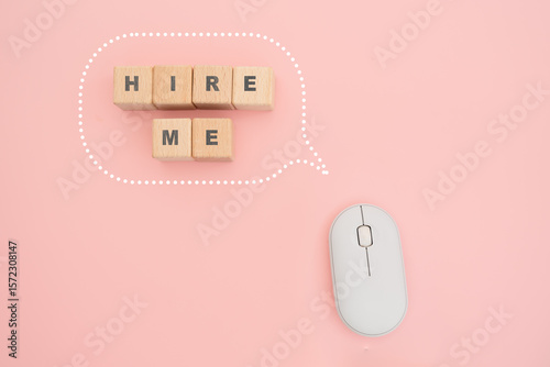 HIRE ME on wooden cube block inside speech bubble and white computer mouse on pink background
