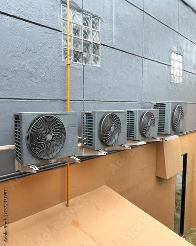 Multiple outdoor air conditioning units, also known as condensers, mounted on the side of a building.