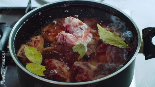 Dropping a bay leaf into a black pot filled with broth