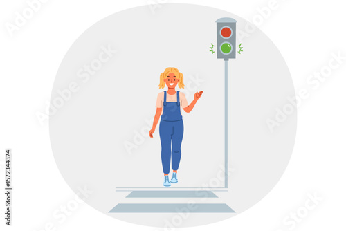 Traffic light shows green signal for little girl walking along pedestrian crossing. Child observes rules of road while strolling around city, and points to traffic light allowing start of movement