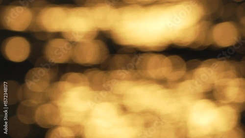 blurry, yellowish-orange sunset over water. The water appears to be rippling and the sky is filled with a warm, golden glow.