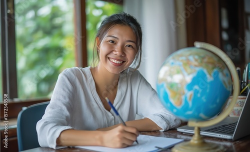 Young woman studying geography at home with globe
