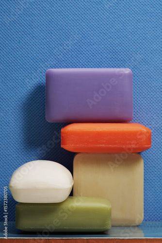 Still life variety of colorful homemade soap bars against textured blue background
