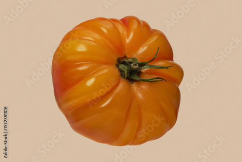 Close up shot of heirloom giant Belgium yellow beef tomato against beige background
