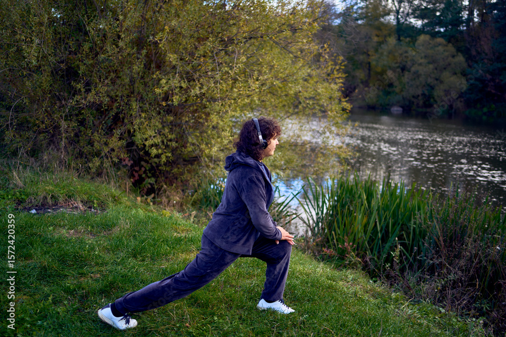 middle-aged woman exercising and switching music in her wireless headphones using her phone during a morning jog in an autumn park middle-aged woman exercising and switching music in her wireless headphones using her phone during a morning jog in an autumn park