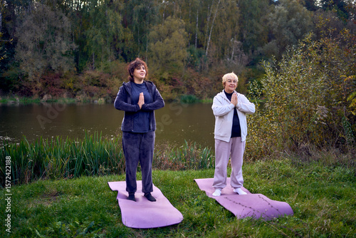 Canvas Print middle-aged woman teaches her old mother somatic exercises and yoga to maintain