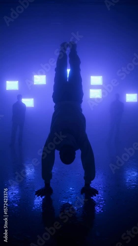 A captivating display of athleticism features an individual performing a handstand in a dimly lit environment with blue ambient lighting, creating a mysterious atmosphere