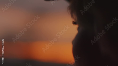 Profile portrait of young beautiful girl who admires amazing sunset from car window during travel. Handheld pov shot of camera. Concept of human emotions
