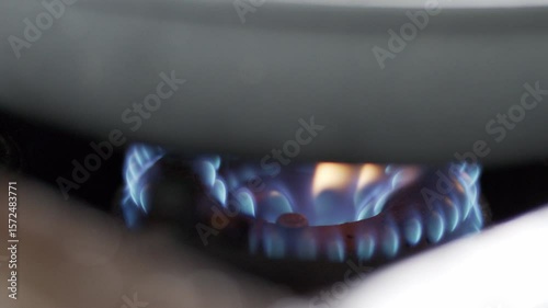 4K footage close-up blue gas flame heating a pan on a stove, intensity and color of the fire used in cooking.