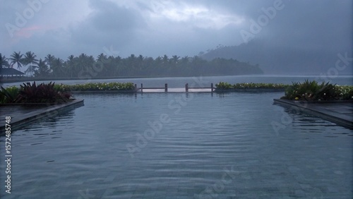 Where the still pool meets the misty horizon in a tropical embrace.