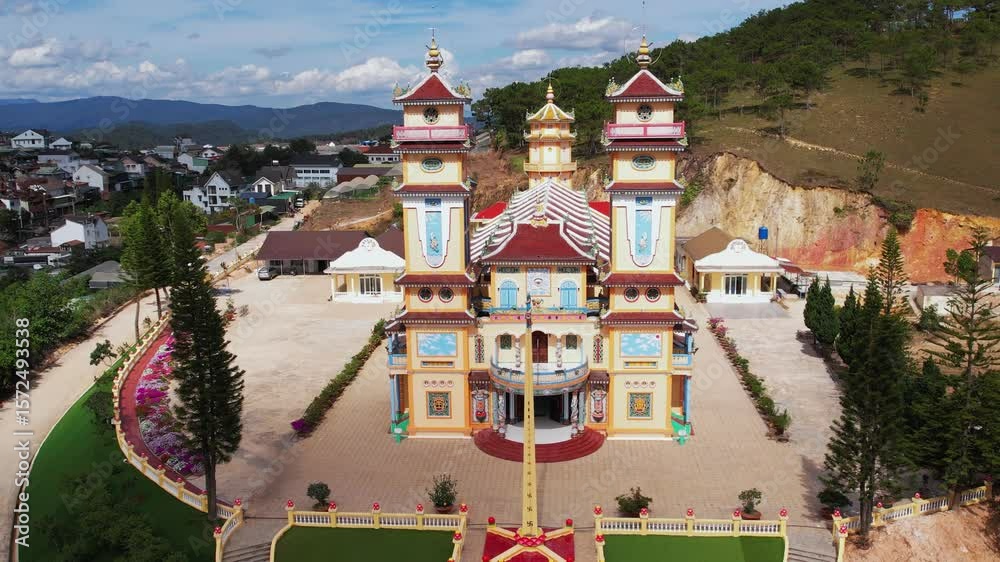 Aerial view of a vibrant, colorful Cao Dai temple in Vietnam, nestled amidst a residential area.  The temple's intricate architecture and surrounding landscape offer a captivating visual. 
