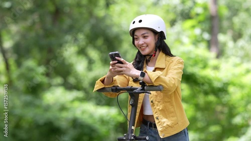 Young woman using smartphone while riding electric scooter