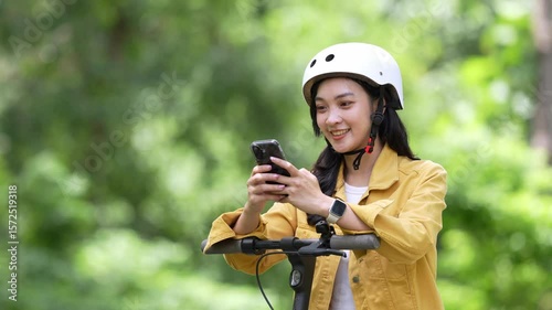Young woman using smartphone on electric scooter in park