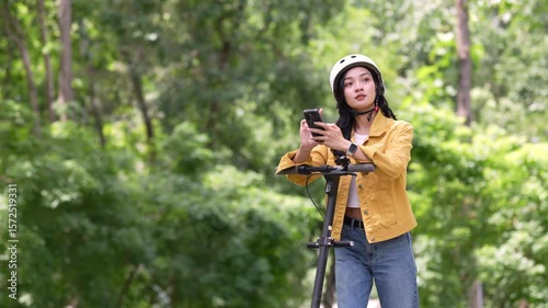 Young woman navigating on phone while standing on scooter