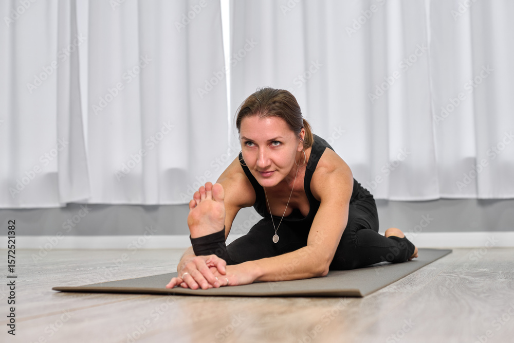 © TRAVELARIUM - Young white female deeply focused in yoga pose, stretching on mat in bright, minimalist room. Captured from low angle, scene evokes calmness and concentration © TRAVELARIUM - Young white female deeply focused in yoga pose, stretching on mat in bright, minimalist room. Captured from low angle, scene evokes calmness and concentration