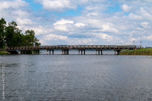 Wallpaper Mural Scenic Low Bridge over Calm Lake with Reed Banks and Forest Background – Rural Infrastructure . 08.07.2025. Alūksne. latvia. Torontodigital.ca