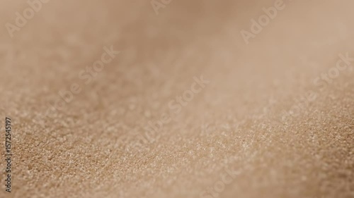 Closeup of light brown textured fabric with fine granular surface details subtly blurring into the background