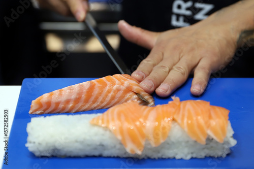 experto en sushi cortando pescado crudo para elaboración de sushi con arroz