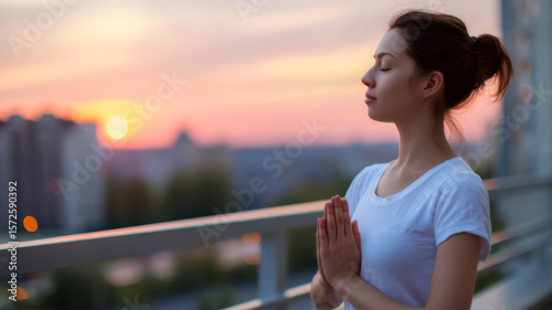 Woman meditates at sunset on balcony