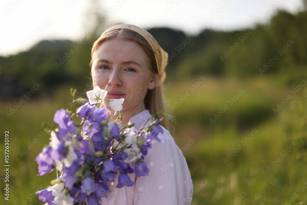 Fototapeta premium Beautiful woman with bouquet of wildflowers in meadow on sunny day. Space for text