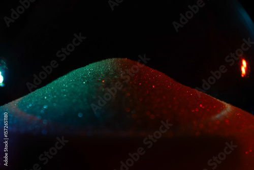 Fototapeta Naklejka Na Ścianę i Meble -  Rainbow sparkly hourglass sand on dark background. Minimalist low key poto for concepts of time, travel to the desert