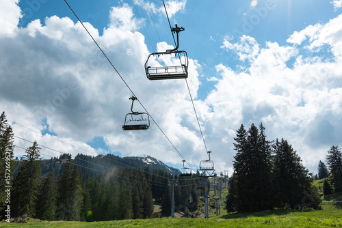 Empty and unoccupied ski lift during summer, Chatzenberg, Swiss Alps. Switzerland, Canton St. Gallen. Sky with clouds. Hiking, traveling, tourism, destination, recreation, leisure activity.