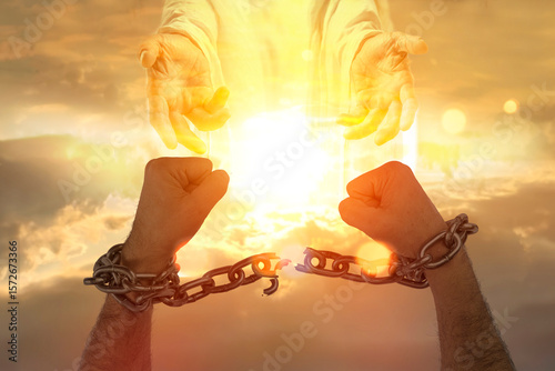 Men's hands breaking chains against the sky with a symbolic hands of Christ the Savior. Concept of christian religion