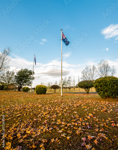 Australian flag moving in breeze with autumn eaves under flag pole