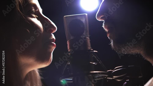 Man and woman recording voices on microphone in dubbing studio